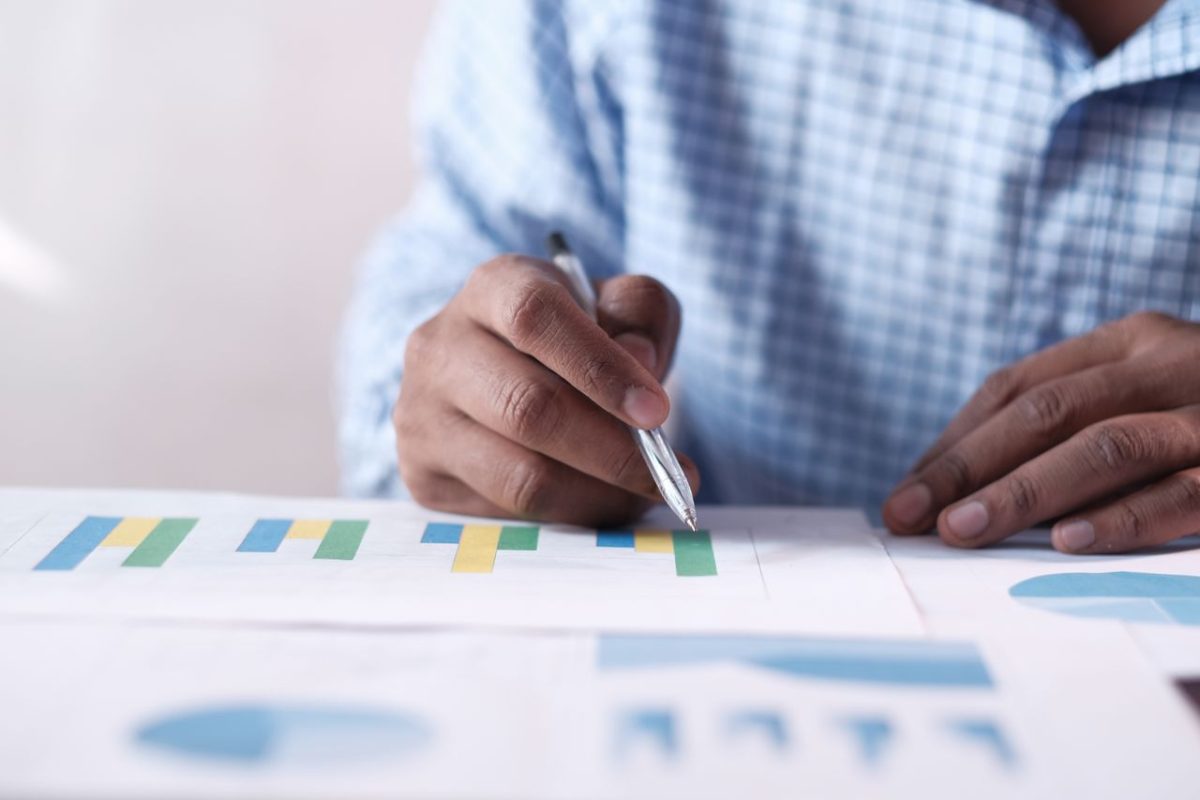 Close-up of hands analyzing colorful graphs, indicating business planning.
